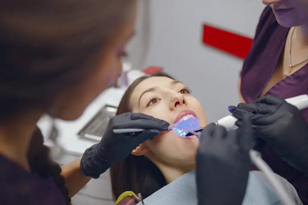 Dentist performing professional teeth whitening treatment on a patient in a dental clinic.