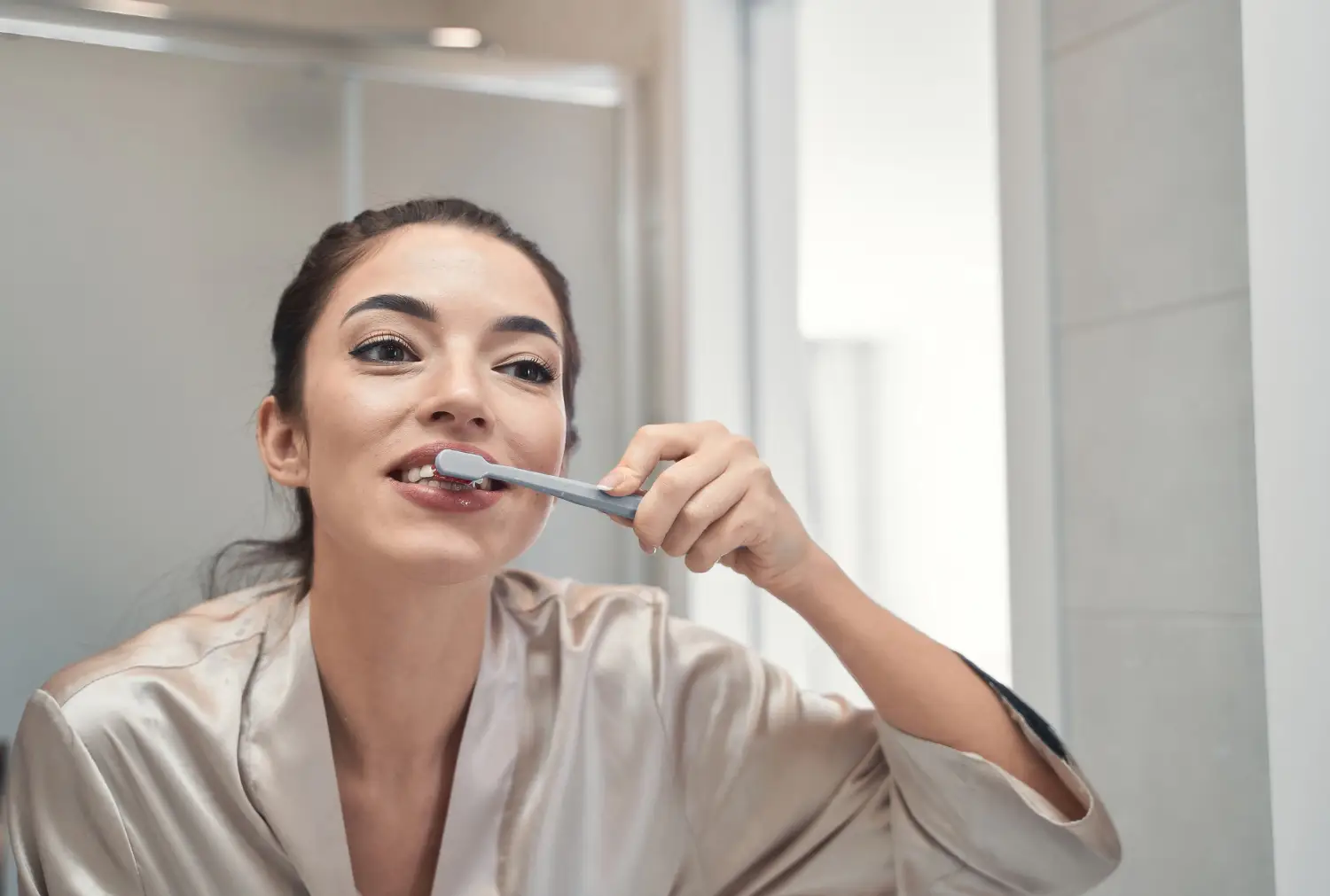 Woman brushing her teeth at home, demonstrating an at-home oral care routine for maintaining a bright, healthy smile.