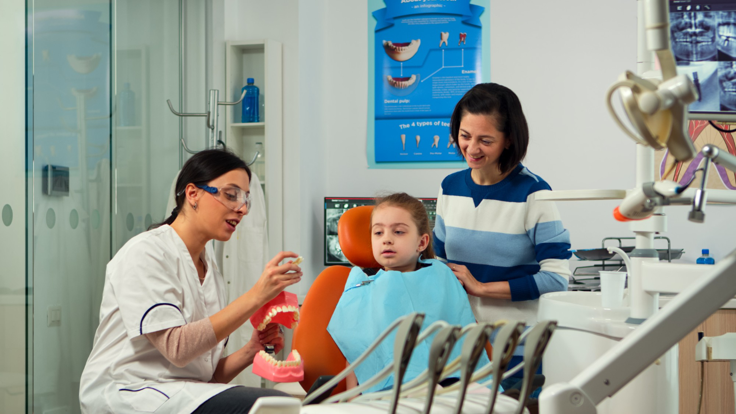 Pediatric dentist explaining dental sealant treatment to a child during a dental appointment.