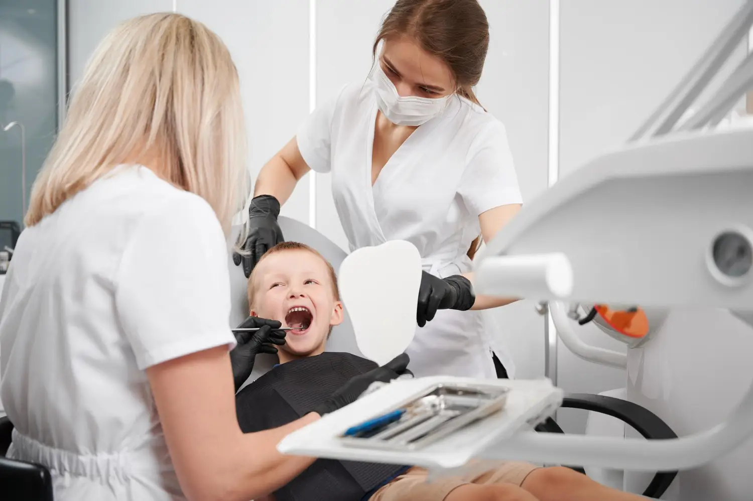 Pediatric dentist examining a child’s teeth during a dental checkup for signs that may require baby tooth extraction.