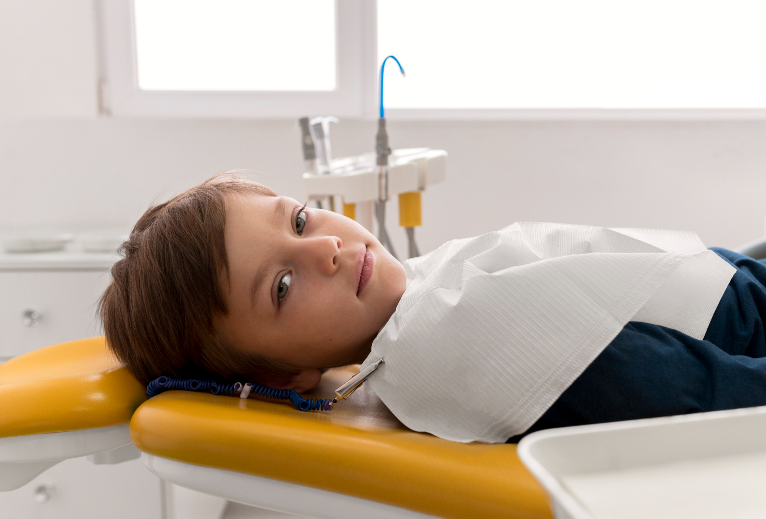 Child resting in a dental chair during a pediatric tooth extraction appointment.