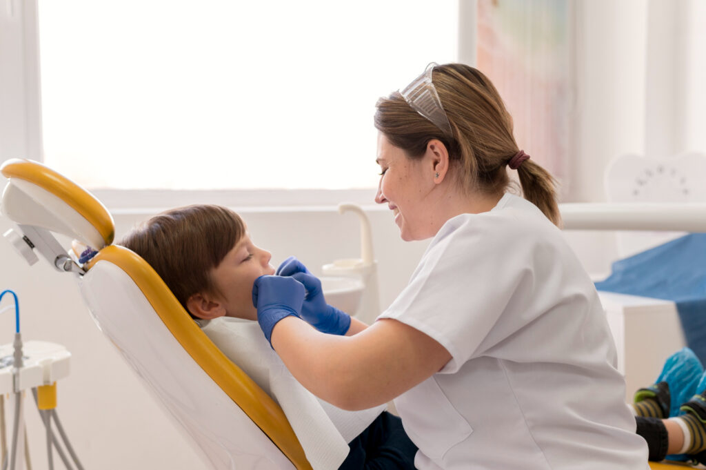 Pediatric dentist examining a childโs teeth during a dental checkup for baby tooth care.