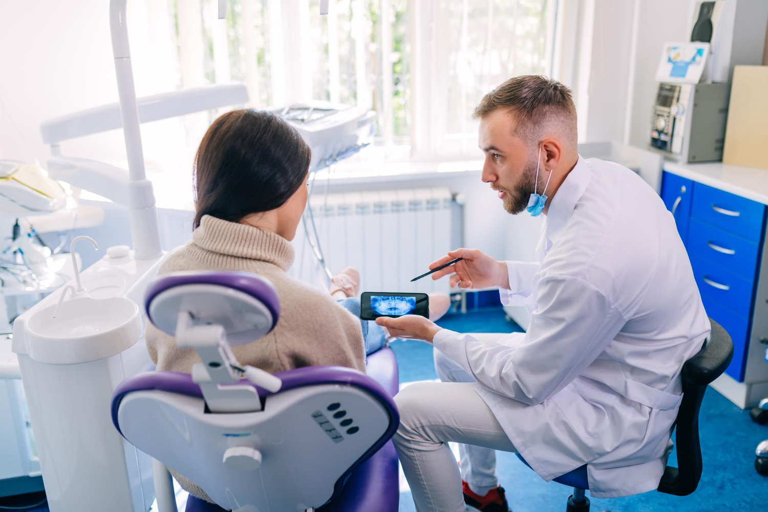 Oral surgery consultation in North Wales, PA with dentist explaining dental X-rays and treatment options to a patient.